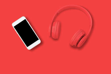 a red headphones, Top view of headphones and smart phone on red background. Minimalist photo of earphones with copy space. red dj headphones, red headphones red backgroundの写真素材