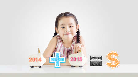 Little girl putting money on a piggy bank with a new year 2015.saving concept from 2014 until 2015...