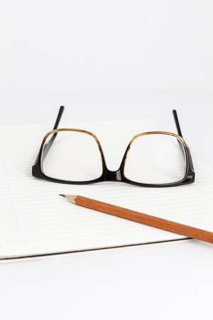 red eyeglasses on a notebook with a pancilの写真素材
