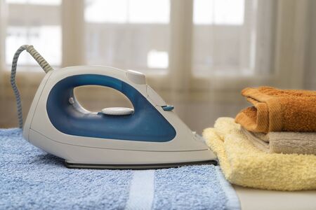 Electric iron and towels on ironing boardの写真素材