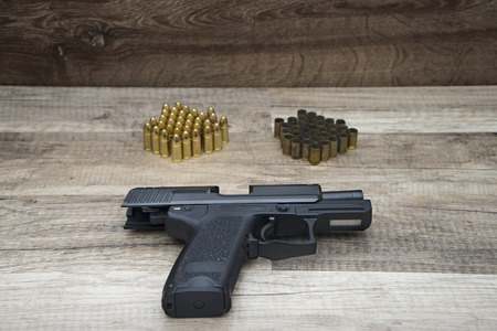 Gun pistol with new and used bullets on wooden background.