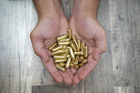 Many bullets into man's masculine hands, with wooden background