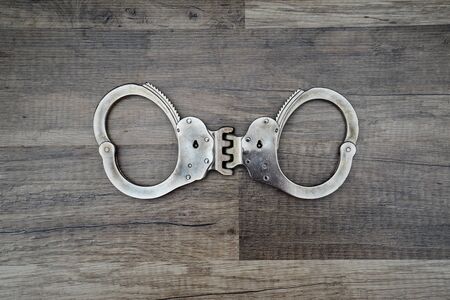 Closeup shot of metallic handcuffs over wooden backgroundの写真素材