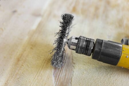 Electrical rotating brush metal disk sanding a piece of woodの写真素材