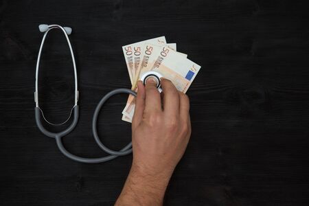 Stethoscope on top of euro banknotes, on black backgroundの写真素材