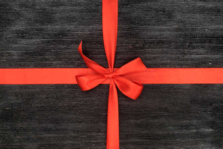 Decorative red ribbon and bow over wooden backgroundの写真素材