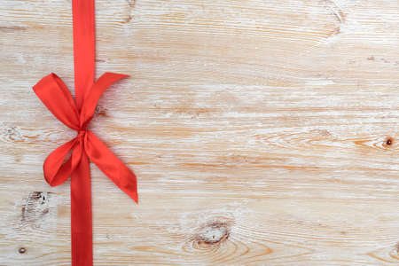 Decorative red ribbon and bow over wooden backgroundの写真素材