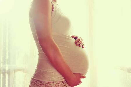 Image of pregnant woman touching her belly with hands