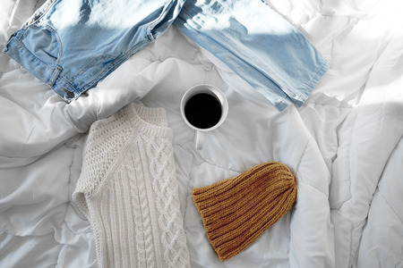 Female outfit and a cup of coffee laid out on bed, morning lightの写真素材