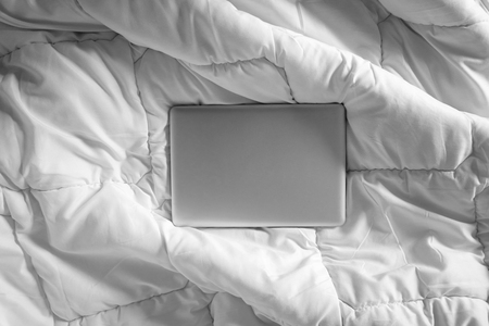 Working in bed , laptop on white bed, morning lightの写真素材