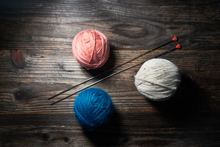 Balls of yarn with knitting needles isolated on wooden backgroundの写真素材