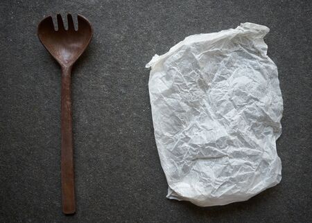Vintage wooden cooking fork and baking paper on black marble backgroundの写真素材