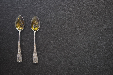 Olive oil in vintage spoons on black marbleの写真素材