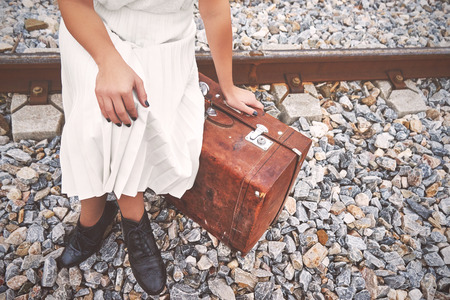 Lonely woman with a suitcase traveling by rail autumn day.の写真素材