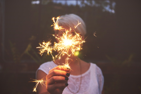 Blonde woman having fun with a sparkler.の写真素材