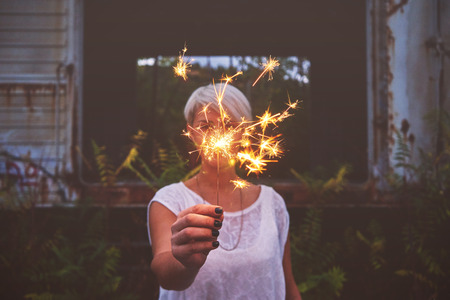 Blonde woman having fun with a sparkler.の写真素材