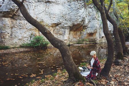Vintage concept with a young woman sitting in the tree and typing on a typewriter
