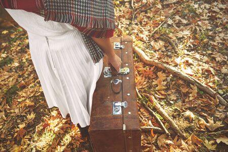 Lonely woman with a suitcase walking in the forest an autumn day.の写真素材