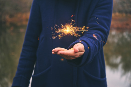 Woman holding sparkler in forest, winter dayの写真素材
