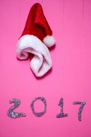 Santa Claus hat on pink background and glitter write 2017