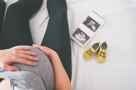 Young pregnant woman relaxing on sofaの写真素材