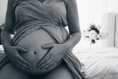 Close up of pregnant woman touching her belly with handsの写真素材
