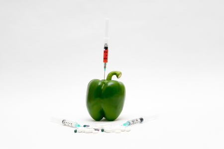 GMO concept on white background with  syringes, pills and pepperの写真素材