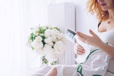 Pregnant woman looking at ultrasound scan of babyの写真素材