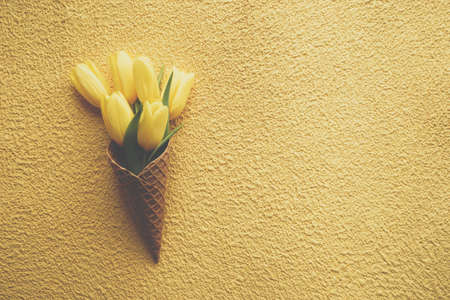 Tulips in ice cream cone on yellow backgroundの写真素材