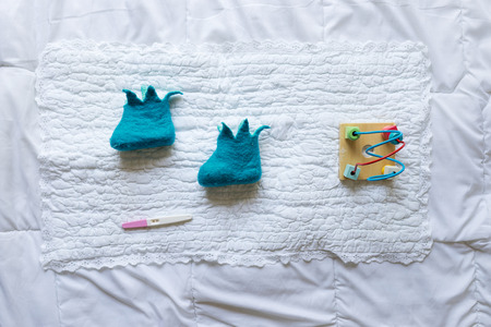 Baby shoes with toys and pregnancy  test on white backgroundの写真素材
