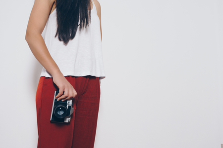 Woman holding a vintage camera front a white backgroundの写真素材