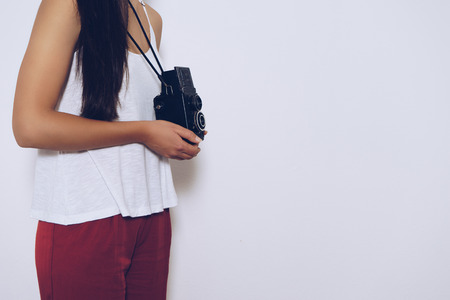 Woman holding a vintage camera front a white background