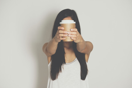 Woman holding brown paper cup of hot coffee.の写真素材