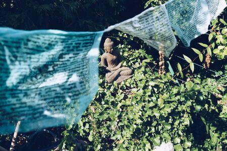 Buddha sculpture on green nature and buddhist prayer flagsの写真素材