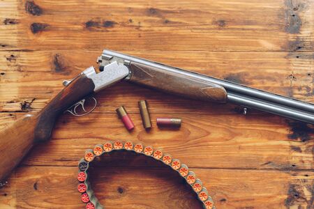 Hunting equipment. Shotgun and hunting cartridges  on wooden table.