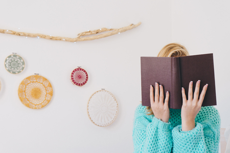 Young woman sitting in bed while reading a bookの写真素材