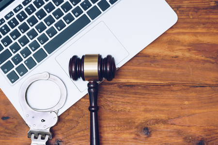 Handcuffs and judge gavel on computer. Concept of internet crime, hacking and cyber crimes の写真素材