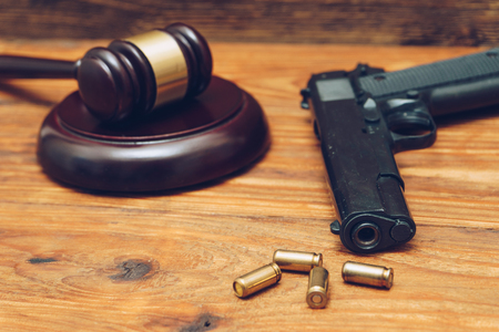 Judge gavel, handgun Î±Î½Î´ bullets on wooden backgroundの写真素材