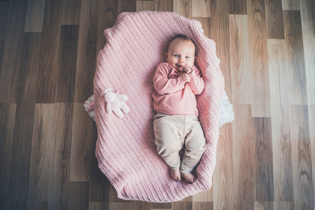 Cute baby lying in the basket, top view.