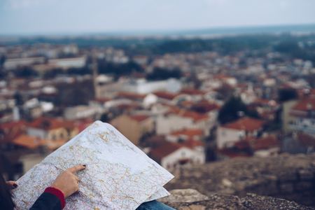 Young girl standing in front of beautiful city view and looking at the map.Panoramic viewの写真素材