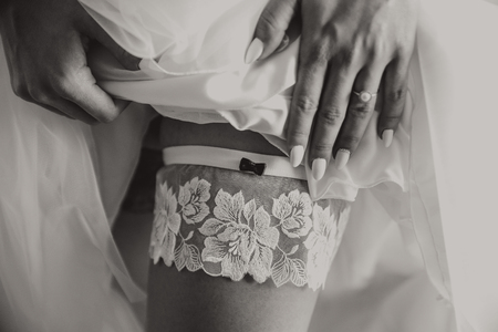 Bride putting a wedding garter on her legの写真素材