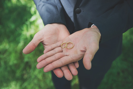 Two golden wedding rings on groom's palms. Wedding rings on the palm. の写真素材