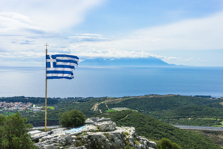The Greek National Flag waving over seascape and Samothraki island as background, summer travel vacation.の写真素材