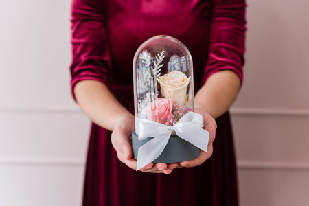 Womans hands holding long-lasting roses in a glass domeの写真素材