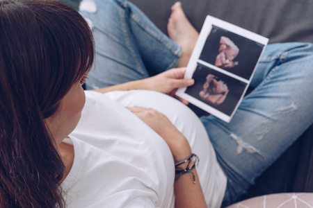 Pregnant woman holds ultrasound photoの写真素材