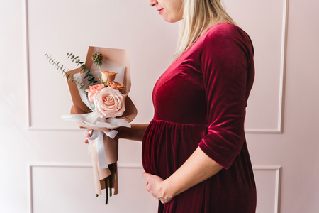 Pragnant woman holding a bouquet of flowersの写真素材