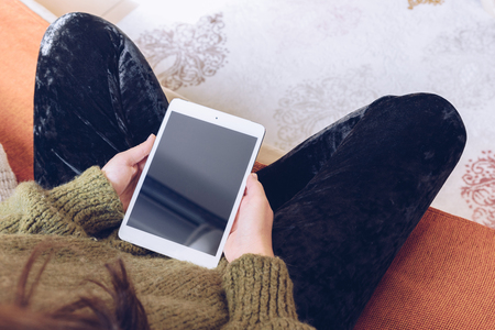 Woman using her tablet sitting on sofaの写真素材