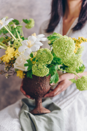 Young woman in a white dress holding vase with flowers. Vintage, romantic concept.の写真素材