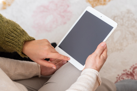 Adult woman and daughter using  tablet with blank screen.の写真素材