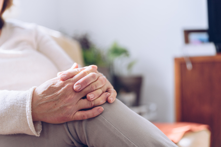 Close up of senior woman hands while sitting on the sofaの写真素材